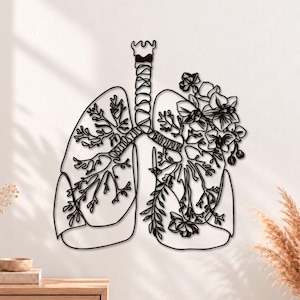 May include: A black metal wall art piece depicting the human respiratory system, featuring a trachea and lungs outlined in wire. The left lung shows bronchial tree branches, while the right lung is filled with detailed floral and leaf patterns.