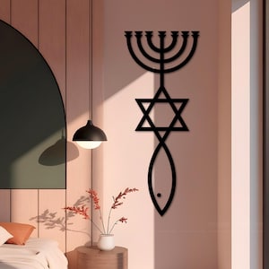 May include: Black metal wall art featuring a menorah, Star of David, and fish symbol. The artwork is mounted on a light pink wall, with a modern design aesthetic. The symbols are connected in a vertical arrangement.