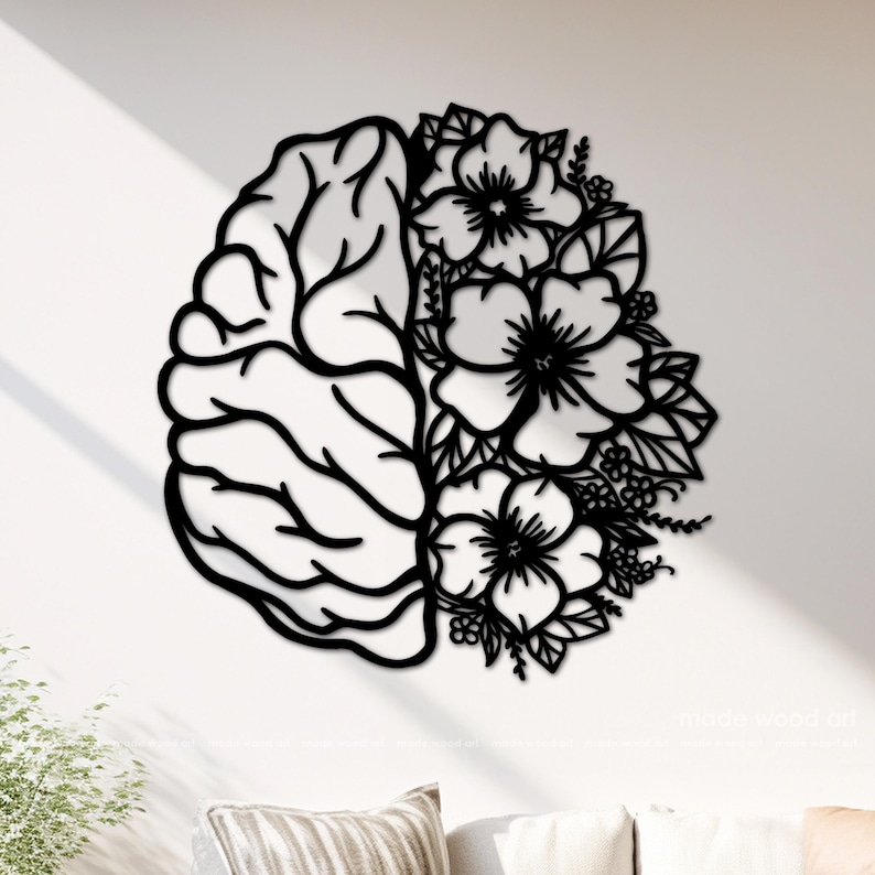 May include: A black wall art piece featuring a split design. The left side depicts the anatomical structure of a human brain with distinct lobes and folds, while the right side is composed of detailed floral arrangements with leaves and petals.