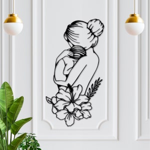 May include: Black metal wall art depicting a mother and child embracing, with a large hibiscus flower below them.