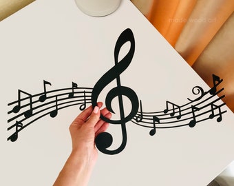 May include: Black metal music notes and treble clef wall decor. The notes are arranged in a flowing line with the treble clef at the center. The decor is on a white surface.