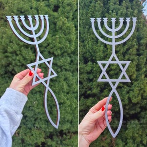 May include: A wooden menorah and Star of David wall hanging. The menorah is silver with a brown border, and the Star of David is silver. The design includes a stylized fish shape. The background is green.