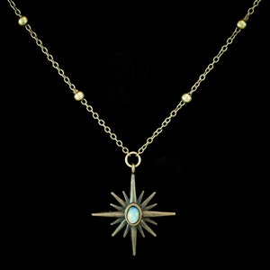 May include: A gold chain necklace with a starburst pendant featuring an iridescent opal stone.