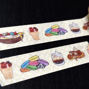 May include: Washi tape with a repeating pattern of illustrated desserts. The design includes ice cream cones, macarons, parfaits, and a banana split, set on a light yellow background with small white polka dots.