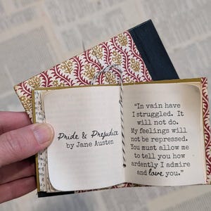 May include: A miniature book titled Pride & Prejudice by Jane Austen with a patterned red and gold cover. The open pages display the text: In vain have I struggled. It will not do. My feelings will not be repressed. You must allow me to tell you how ardently I admire and love you.