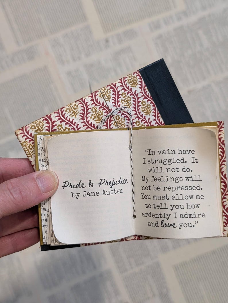 May include: A miniature book titled Pride & Prejudice by Jane Austen with a patterned red and gold cover. The open pages display the text: In vain have I struggled. It will not do. My feelings will not be repressed. You must allow me to tell you how ardently I admire and love you.