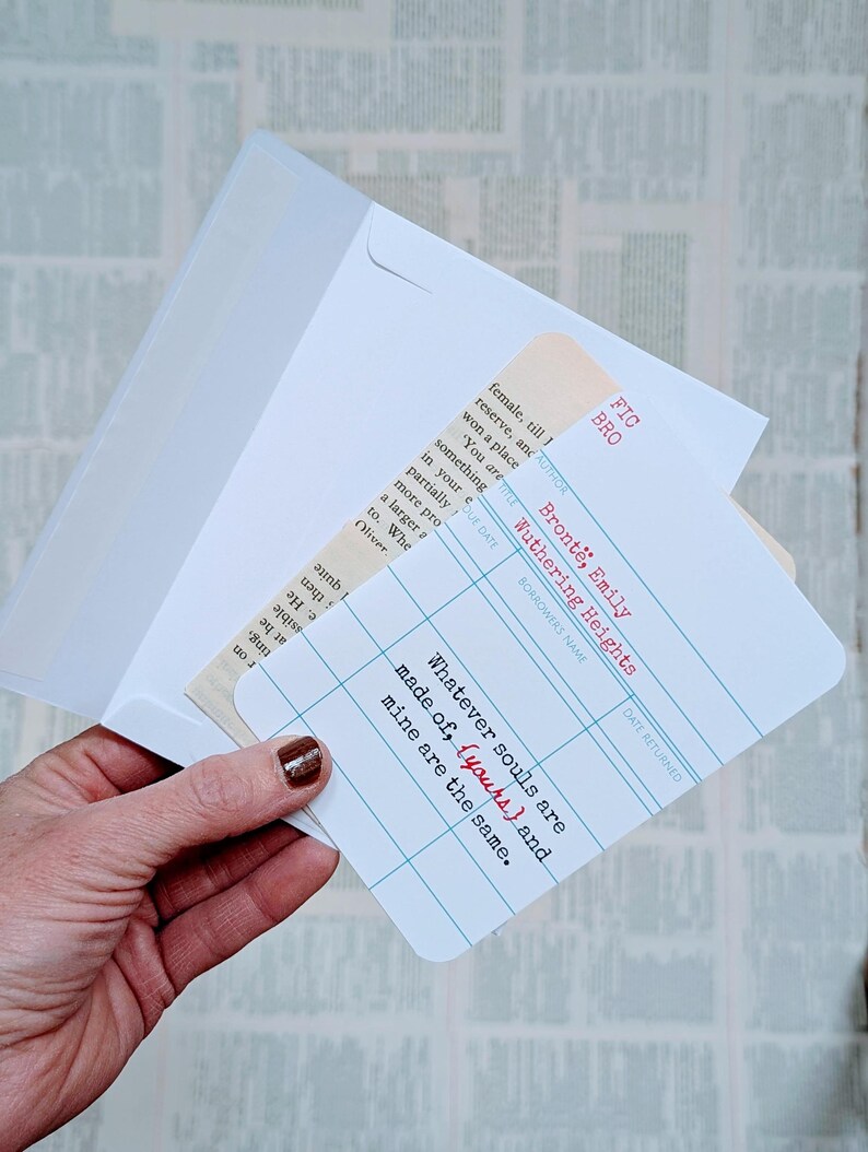 May include: A white envelope holds a card with a library card design. The card features the quote "Whatever souls are made of, (yours) and mine are the same." in red and black text. The card is a literary-themed item.