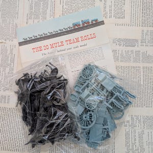 May include: A set of three ceramic mugs with a speckled, cream-colored glaze. Each mug features a different hand-painted design: a blue and green leaf, a yellow flower, and a red berry. The mugs have a simple, modern design.