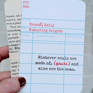 May include: A white card with blue grid lines and red text, resembling a library card, features the title "Wuthering Heights" by Emily Bront&euml;. The quote "Whatever souls are made of, {yours} and mine are the same" is printed on the card.