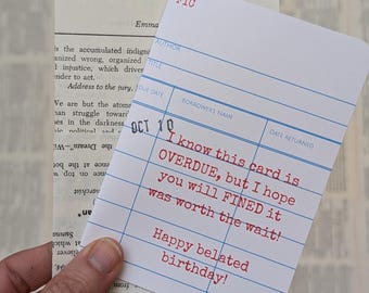 Puede incluir: Una tarjeta de biblioteca blanca con líneas azules y texto rojo que dice "Sé que esta tarjeta está CADUCADA, pero espero que te MULTE por ella porque valió la pena la espera! ¡Feliz cumpleaños atrasado!"