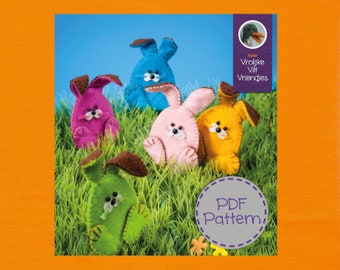Op de afbeelding: Vijf vilten konijnen speelgoed in verschillende kleuren, waaronder roze, blauw, groen, geel en paars. De konijnen zitten op een bed van groen gras. De tekst "PDF Pattern" staat in een cirkel rechtsonder in de afbeelding.