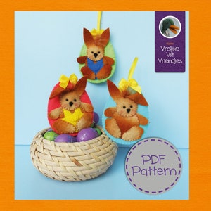 May include: Three felt Easter bunny ornaments in the shape of eggs, with yellow, red, and blue accents. The ornaments are in a wicker basket with colourful Easter eggs. The text "PDF Pattern" is on a purple circle with a grey dashed border.