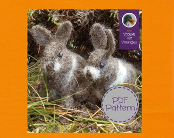 Op de afbeelding: Twee bruine en witte vilt konijnen met zwarte ogen, zittend in een bed van groen gras. De tekst "PDF Pattern!" staat op een grijze cirkel met een paarse rand. De tekst "Atelier Vrolijke Vilt Vriendjes" staat op een paarse rechthoek met een groen eendpictogram.