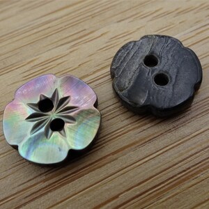 Peut inclure: Deux boutons décoratifs, l'un est noir avec un motif en bois et l'autre est iridescent avec un motif en étoile.