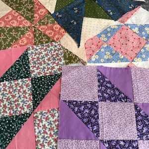 May include: Four square fabric quilt blocks featuring various patchwork designs. The blocks display floral, geometric, and solid patterns in shades of pink, green, blue, purple, and white, constructed from triangular and square fabric pieces.
