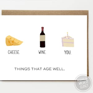 May include: A white card with a cartoon illustration of a wedge of cheese, a bottle of wine, and a slice of cake with a candle. The text reads "CHEESE. WINE. YOU. THINGS THAT AGE WELL."  The card is designed by Wildest Closet.