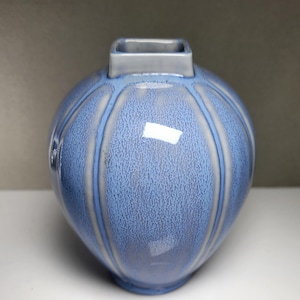 May include: A blue ceramic vase with a textured surface and a square opening at the top.