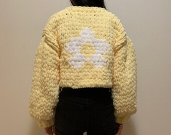 Handknit light yellow chunky chenille knit cardigan with a white flower graphic pattern on the back and white flower shaped buttons