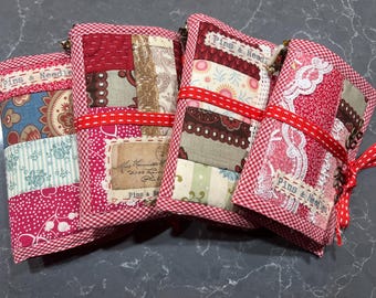 Puede incluir: Cuatro alfileteros de tela de gingham rojo y blanco con diferentes diseños de patchwork. Cada alfiletero tiene una etiqueta que dice "Pins & Needles".