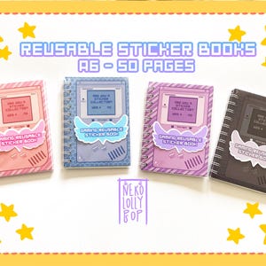 May include: Four spiral-bound sticker books with a retro video game console design. Each book has a different pastel color: pink, blue, purple, and black. The text on the cover reads "REUSABLE STICKER BOOKS A6 - 50 PAGES". Each book has a sticker that says "GAMING REUSABLE STICKER BOOK".