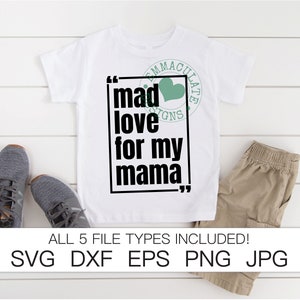 May include: White t-shirt with black text that reads "mad love for my mama" in quotation marks. A green heart is above the text. The shirt is on a white wooden surface.