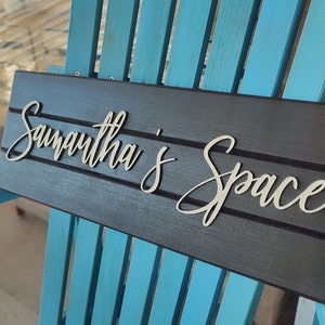 May include: A black wooden sign with the words "Samantha's Space" written in white raised letters.