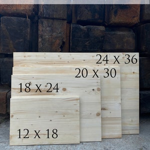 May include: Four wooden boards of different sizes with dimensions marked in inches. The boards are light brown and have a natural wood grain. The text on the boards reads: "24 x 36", "20 x 30", "18 x 24", and "12 x 18".