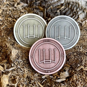 Puede incluir: Tres fichas metálicas redondas con un diseño de corona de cuatro puntas y la palabra "PHUL" inscrita alrededor del borde. Las fichas son de diferentes colores: oro, plata y cobre.