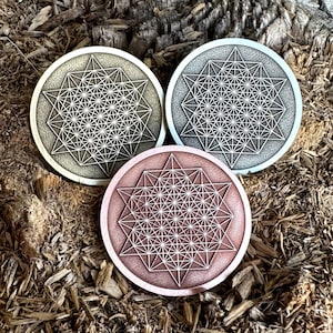 May include: Three round metal coasters with a geometric pattern. The coasters are silver, copper, and gold.