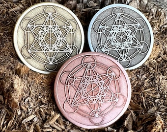 May include: Three round metal coasters with a geometric design. The coasters are in gold, silver, and copper.