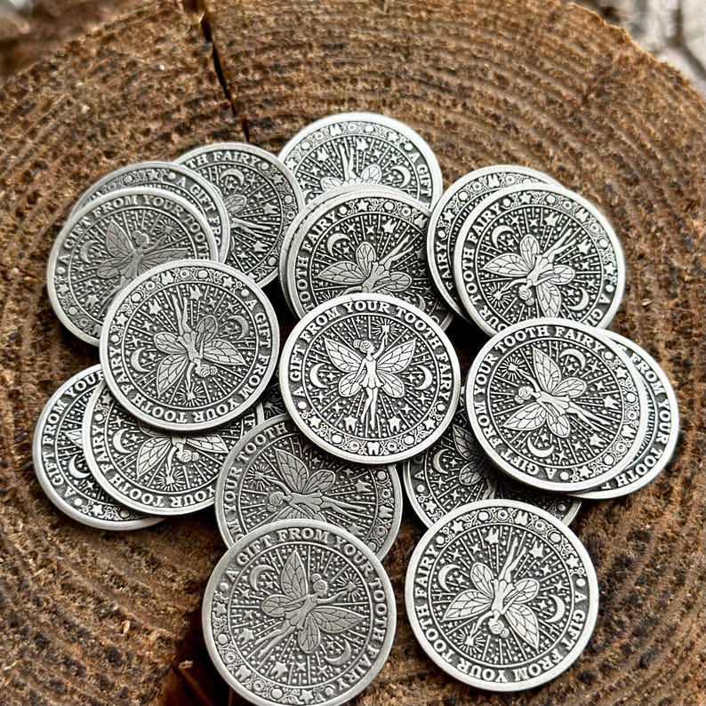 May include: A pile of silver-colored tooth fairy coins with the inscription "A Gift From Your Tooth Fairy" on each coin.