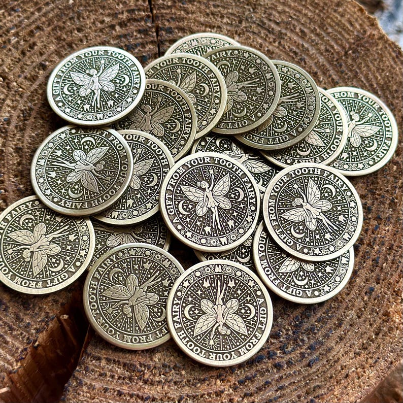 May include: A collection of gold-colored metal tokens with a fairy design and the text "A Gift From Your Tooth Fairy".