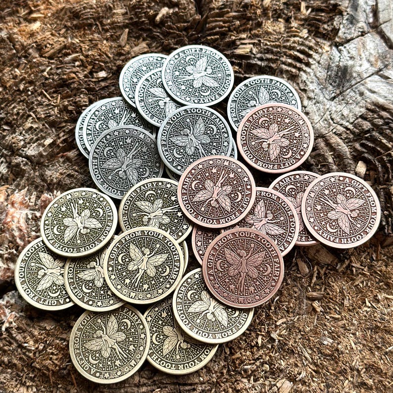 May include: A collection of silver, gold, and copper-toned metal tokens with a fairy design and the text "A Gift From Your Tooth Fairy".
