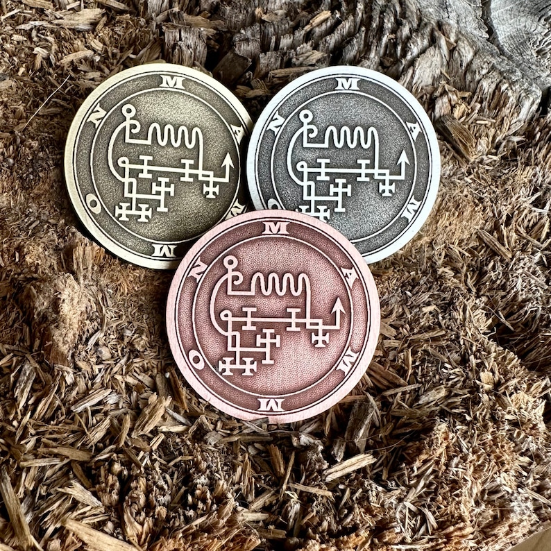 May include: Three metal tokens with sigils inscribed on them. The tokens are in gold, silver, and copper.