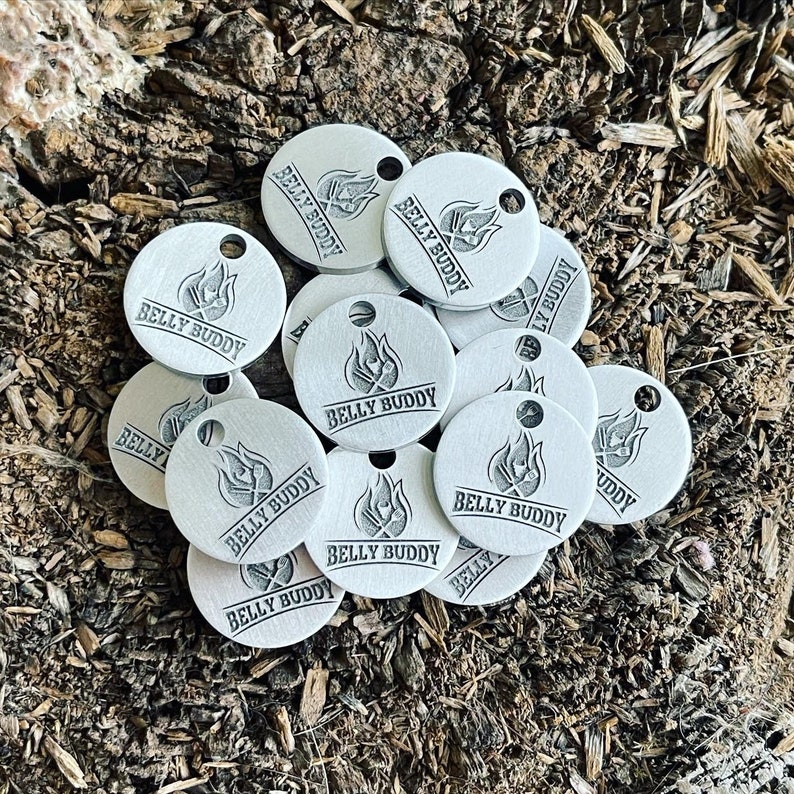 May include: A pile of silver metal tags with the words "Belly Buddy" and a flame design.