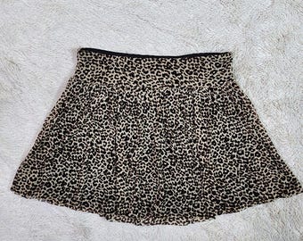 May include: A brown and black leopard print skirt with a black waistband. The skirt is pleated and has a flowy silhouette.