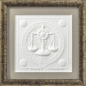 Op de afbeelding: Een witte papieren reliëfsculptuur van het sterrenbeeld Weegschaal, omringd door een cirkel met de tekst "ROMANTIC TALENTED IDEALIST SOCIABLE & POPULAR", "LIBRA" en "ROMANTISKAS TALENTINGAS IDEALISTAS DRAUG", met de handtekening van de kunstenaar "I. Moželytė, Svarstykles." onderaan.