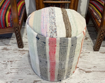 May include: A round, white, and gray striped ottoman with a colorful striped top. The ottoman is made of woven fabric and has a rustic, handmade look.