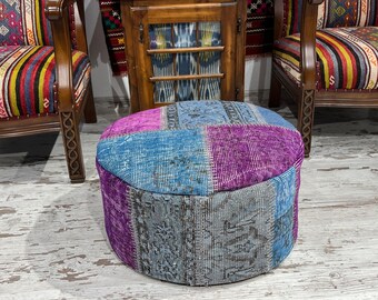 Könnte beinhalten: Ein runder, mehrfarbiger Hocker mit Patchwork-Muster. Der Hocker besteht aus verschiedenen Blautönen und Lila-Stoff. Er steht auf einem weiß getünchten Holzboden.