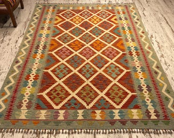 May include: A colorful rug with a geometric pattern in shades of red, green, blue, and yellow. The rug has a fringe border and is woven with a traditional design.