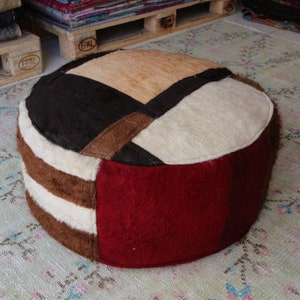 Peut inclure: Un pouf rond multi-colore en patchwork avec un motif brun, blanc et rouge. Le pouf est fait de différents tissus et textures.