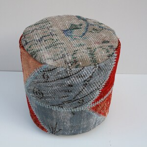 Könnte beinhalten: Ein runder Patchwork-Hocker mit einer beigefarbenen Oberseite und einer Basis aus blauem, rotem und orangefarbenem Stoff.