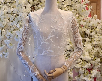 Sequin leaf vine embroidery boat neck lace bridal bolero jacket with open back. Long sleeves with crystal button detail