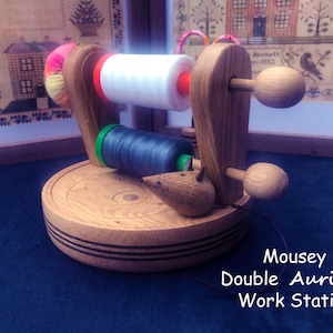 Può includere: Porta-bobine doppio in legno per filo Aurifil con una statuetta di topo, due bobine di filo e il testo "Mousey Double Aurifil Work Station".