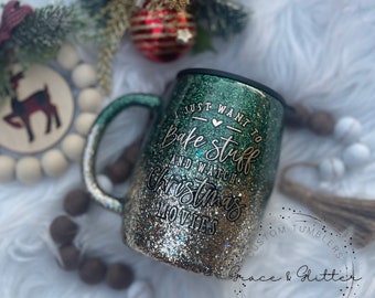 May include: A green and gold glitter tumbler with a black lid and handle. The tumbler has the text "I just want to bake stuff and watch Christmas movies" on it. The tumbler is sitting on a white fuzzy surface.