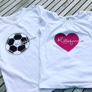 Könnte beinhalten: Zwei weiße T-Shirts mit dem Wort "Köllefornia" bedruckt. Ein Shirt hat einen schwarzen Fußball und das andere ein pinkfarbenes Herz.