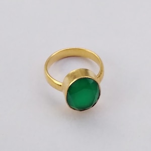 May include: A gold ring featuring a large, round, green gemstone.