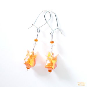 May include: A pair of silver dangle earrings with orange origami flower charms and clear and orange beads.
