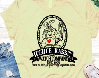 Puede incluir: Una camiseta amarilla con un gráfico en blanco y negro del Conejo Blanco de Alicia en el País de las Maravillas. El gráfico incluye el texto "White Rabbit Watch Company Est. 1951" y "Never be late for your very important date!"