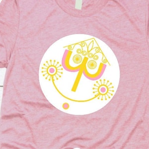 Può includere: Maglietta rosa con un designo giallo e rosa di un albero stilizzato all'interno di un cerchio giallo. Il design ricorda una popolare giostra di un parco divertimenti. Il testo "Jennylynn West SVG" è nella parte inferiore della maglietta.